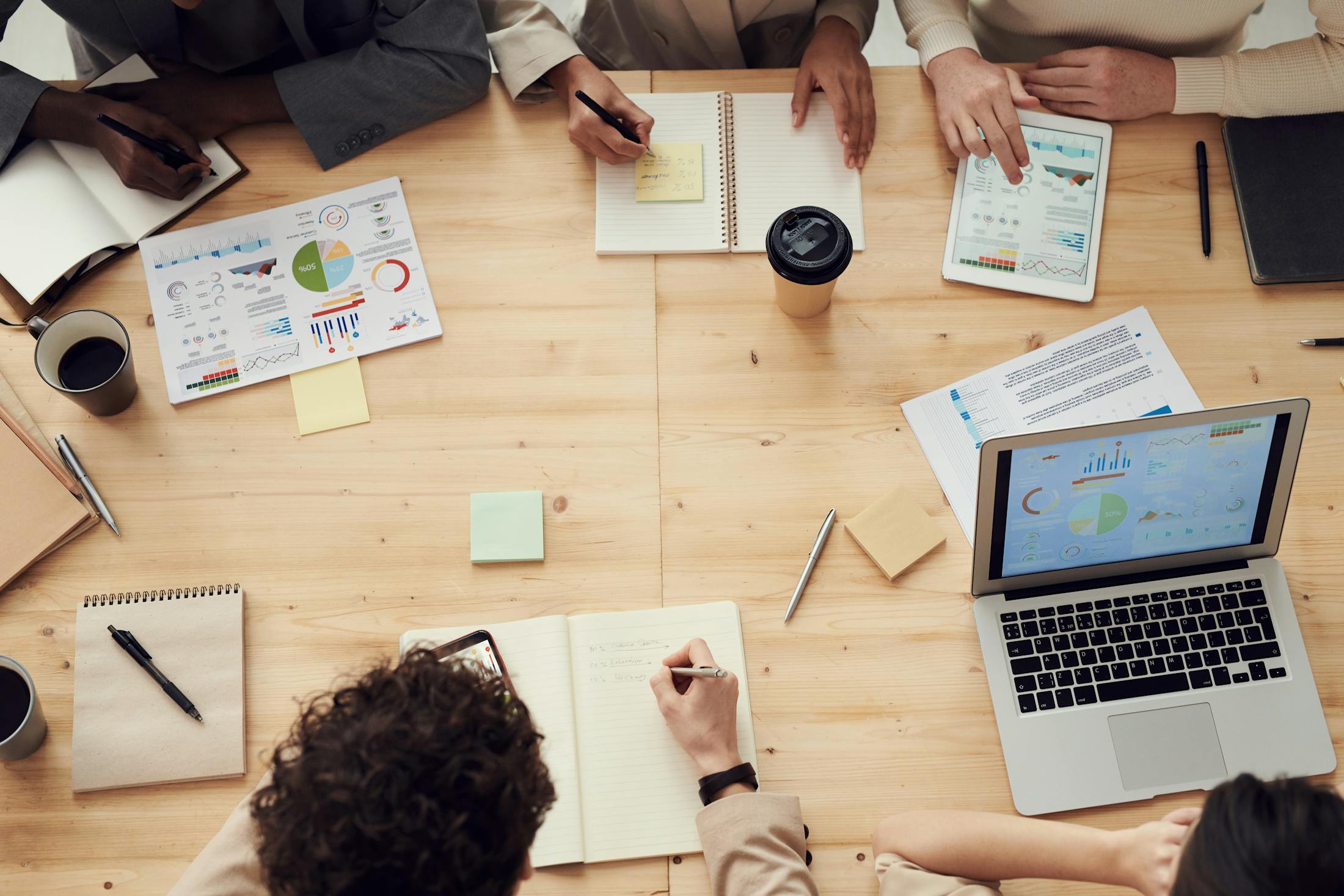 Strategy table with laptops, charts, notebooks, and marketing planning materials